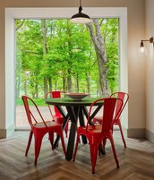 Un comedor con una mesa y sillas, una lámpara colgante y vistas a un bosque a través de un ventanal.