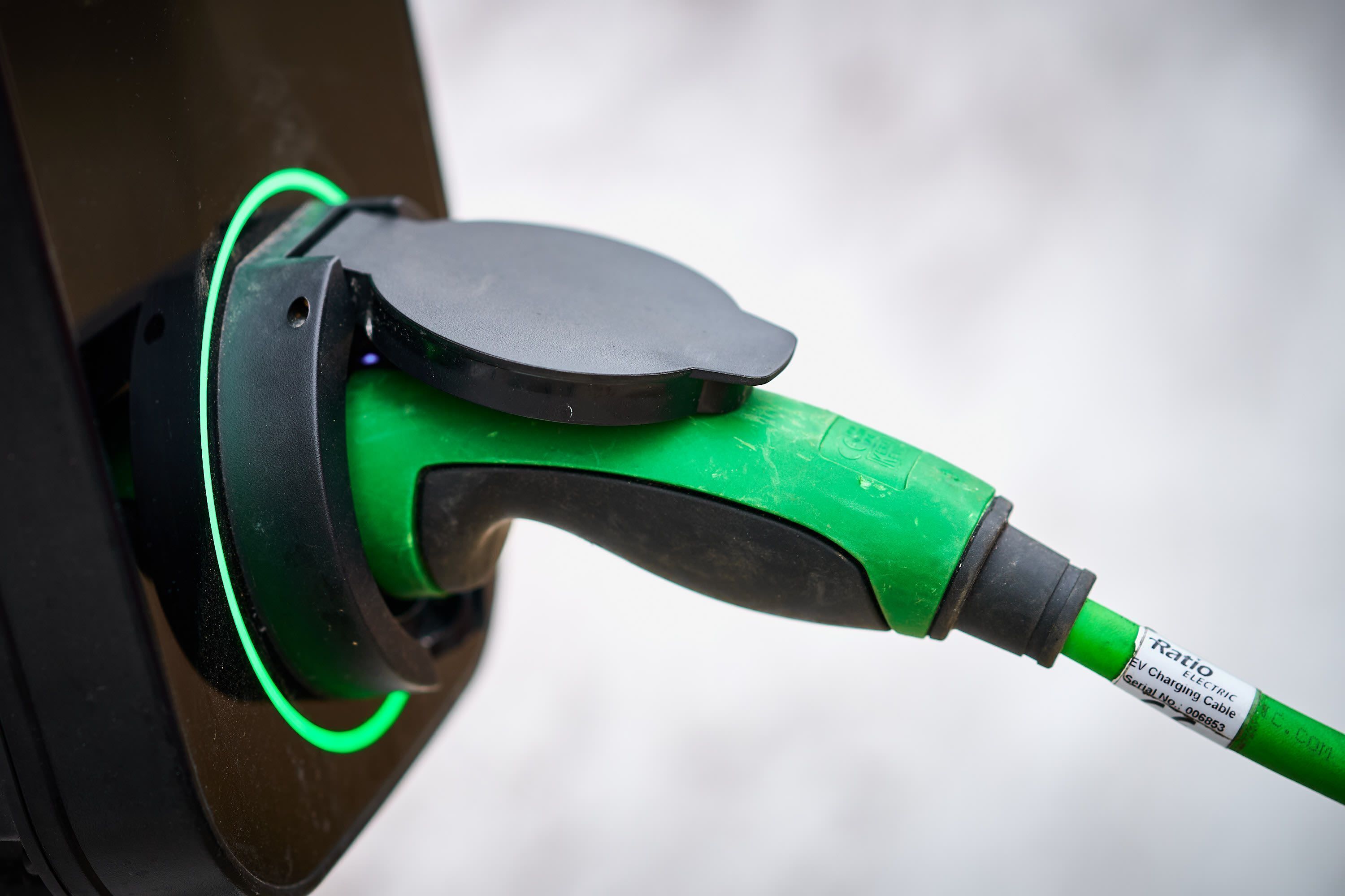 Een groene laadkabel voor elektrische voertuigen, aangesloten op een oplaadstation.
