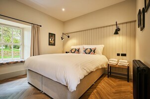 Un dormitorio con una cama grande, una ventana con cortinas, un radiador y una lámpara de pared.