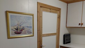 A room with a wooden door, a white cabinet, a framed painting, and a wooden bench. - Apartment in Stamsund (Stamsund)