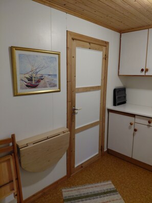 A room with a wooden door, a white cabinet, a framed painting, and a wooden bench. - Apartment in Stamsund (Stamsund)