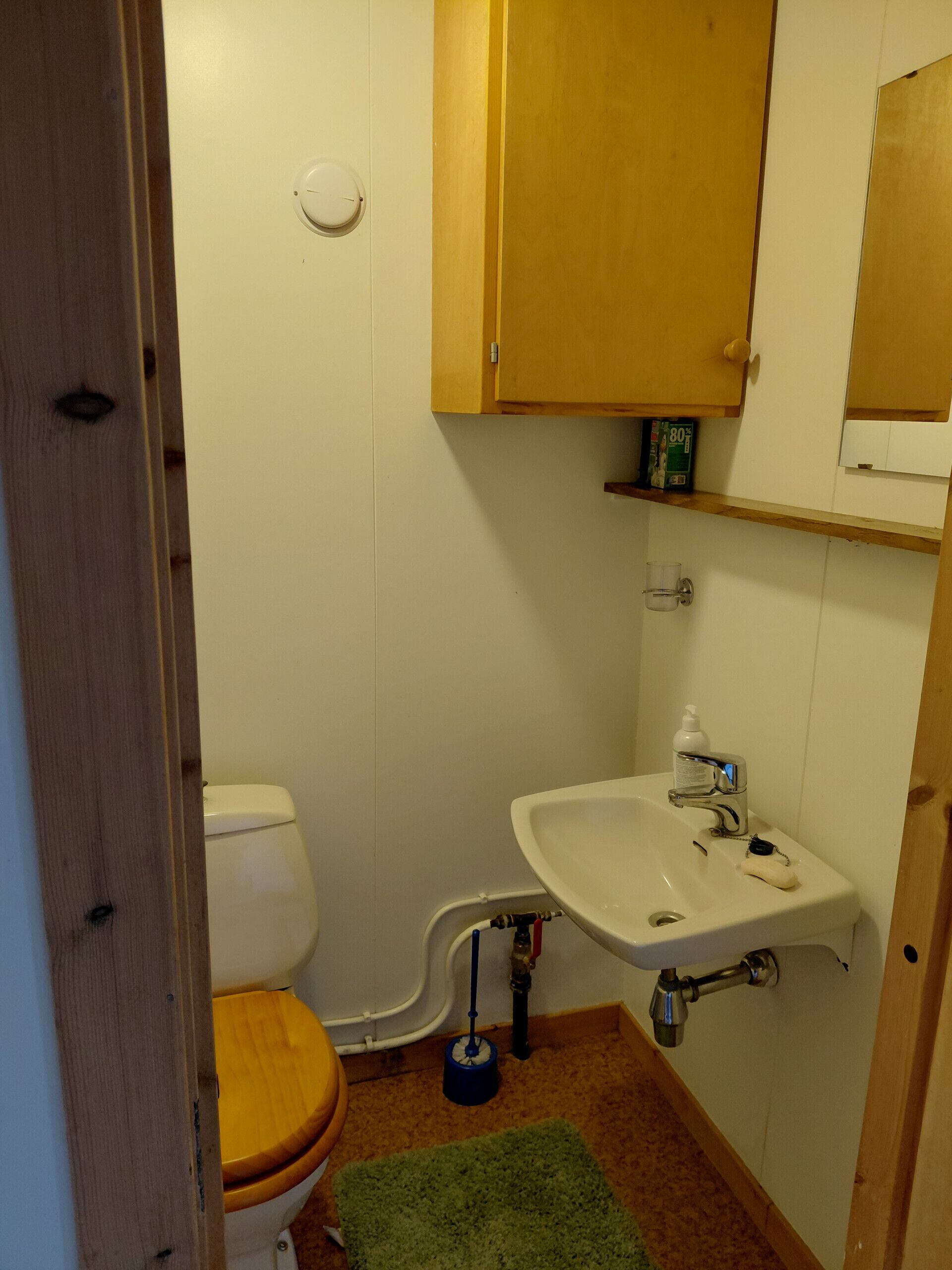 Un baño pequeño con inodoro, lavamanos y ducha.