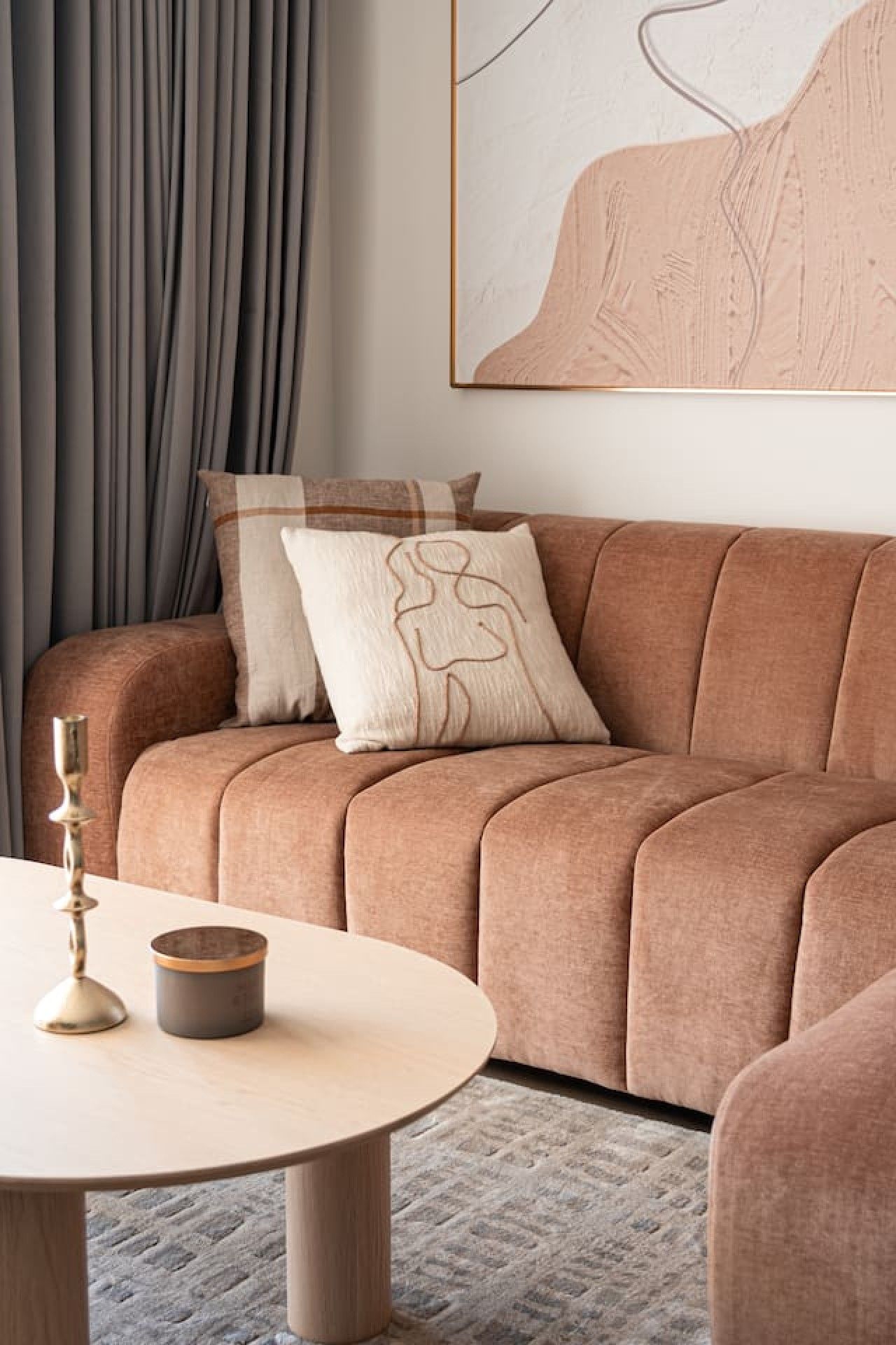 Ein modernes Wohnzimmer mit einem braunen Sofa, einem runden Couchtisch und einem Gemälde an der Wand.