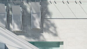 A modern building with a tiled facade and a series of rectangular structures that could be air conditioning units or vents. - Brand-New Premium Retreat|Pool &Gym| Parking|Train (Mitchelton)