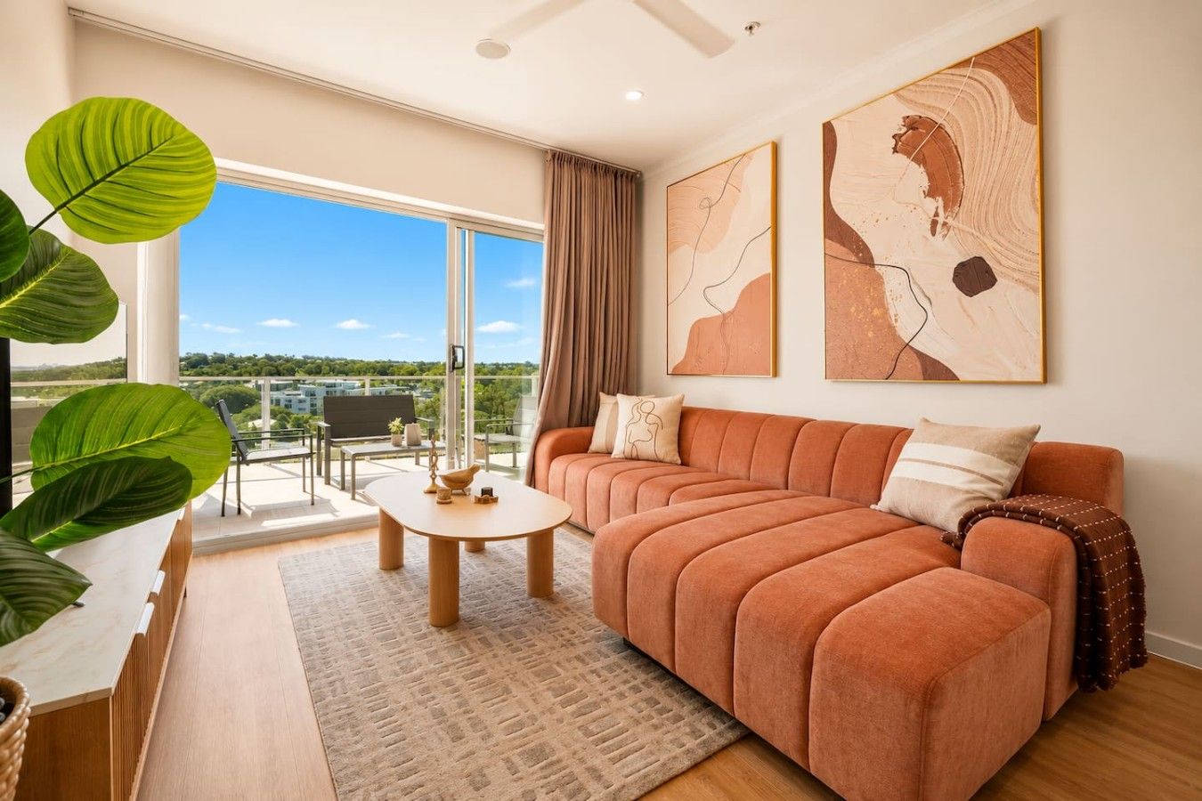 Ein modernes Wohnzimmer mit einer Couch, einem Couchtisch und einem großen Fenster mit Blick ins Freie.
