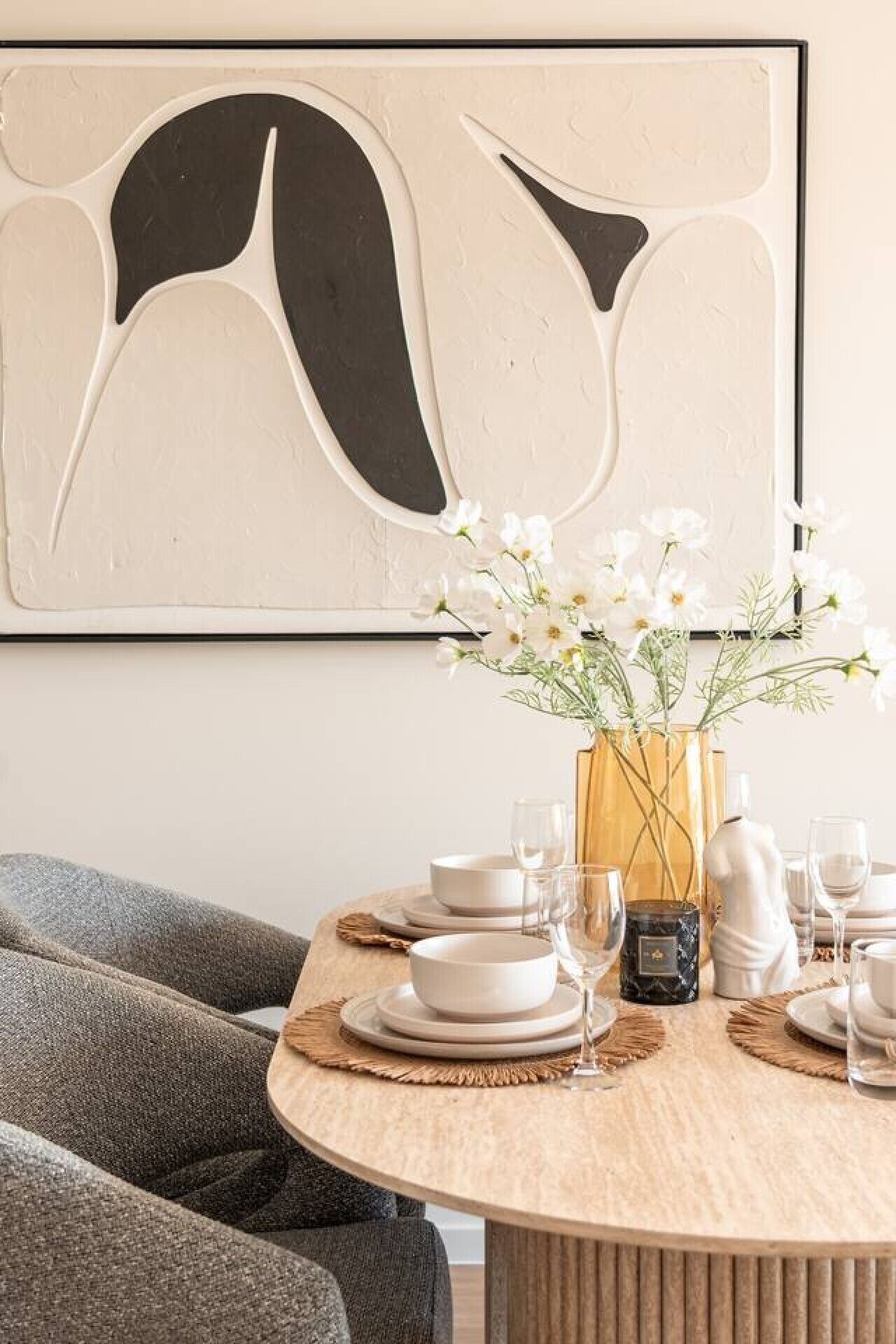 Et spisebord dækket med tallerkener, glas og en vase med blomster.