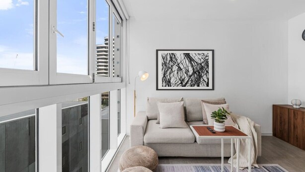 A modern living room with a sofa, cushions, a coffee table, and a framed abstract artwork. - The Valley Great Value| Sofa Bed |Parking|Pool&Gym (Fortitude Valley)