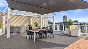 An outdoor patio with a table and chairs, a grill, and potted plants. - The Valley Great Value| Sofa Bed |Parking|Pool&Gym (Fortitude Valley)