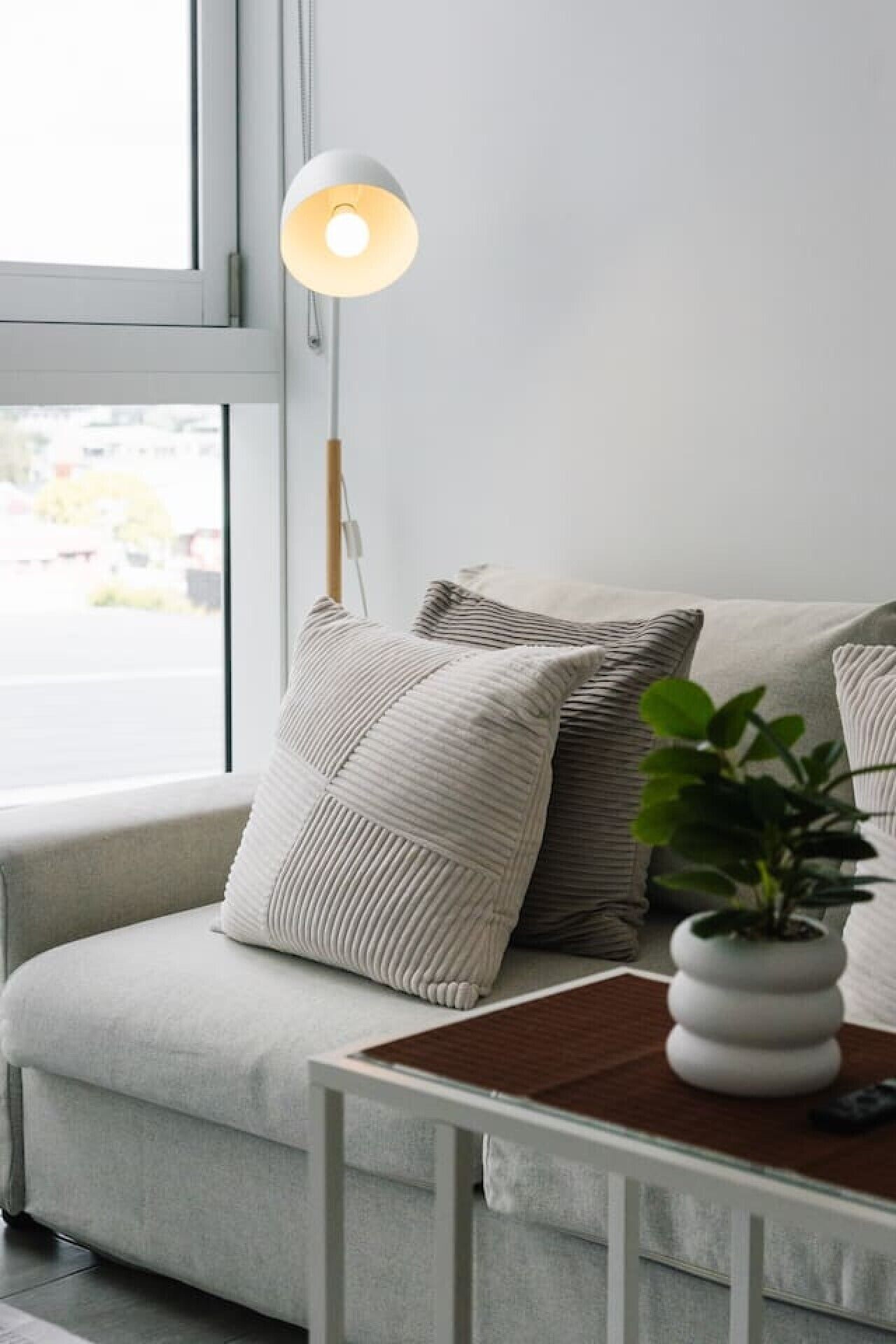Ein modernes Wohnzimmer mit einer Couch, einer Lampe und einem Topfpflanzen.