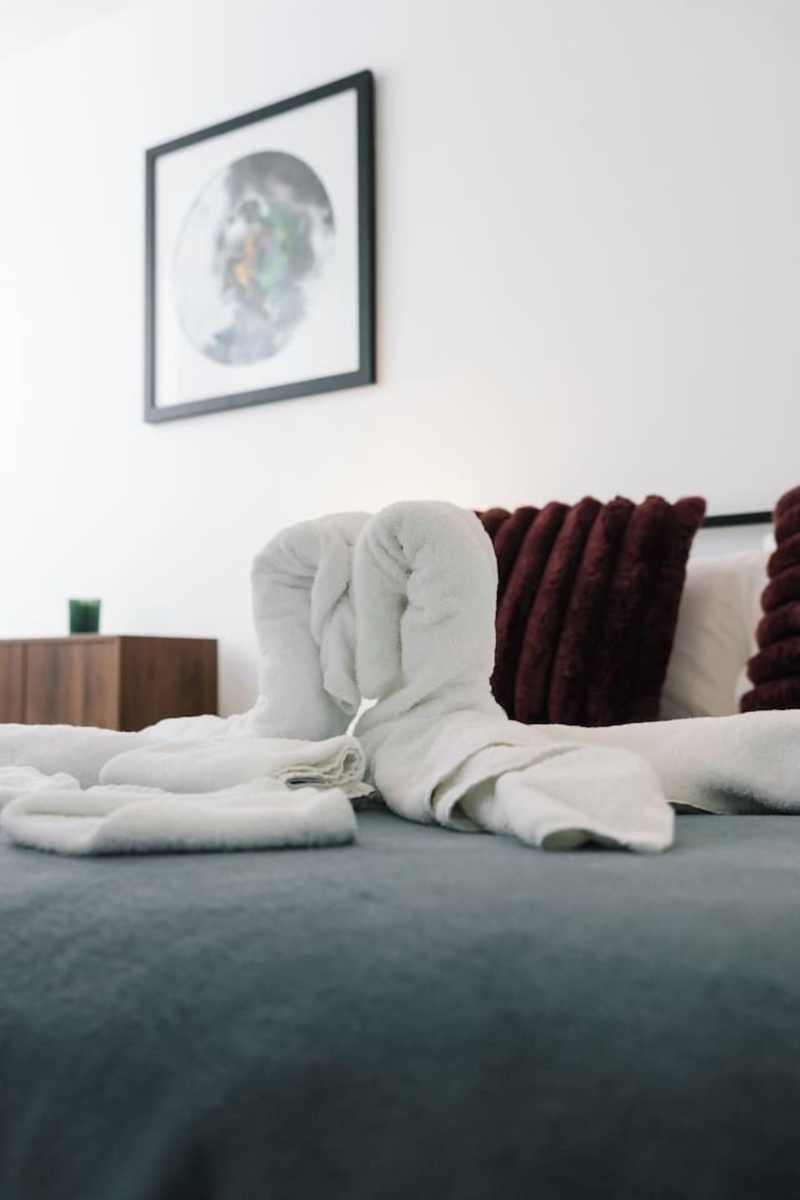 A neatly made bed with a white blanket and a brown pillow.