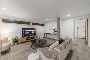 Uma sala de estar moderna com televisão de tela plana, sofá, mesa de centro e luminária.