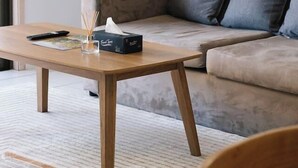 Ein Wohnzimmer mit einer Couch, einem Holztisch und einem Sessel.