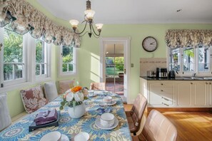 A dining area with a table set for four, a chandelier, and a view of the garden through the window.