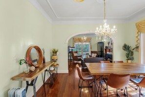A dining area with a long wooden table, multiple chairs, and a chandelier.