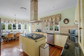 A kitchen with a central island, a dining area with chairs, and a view of the outdoors.