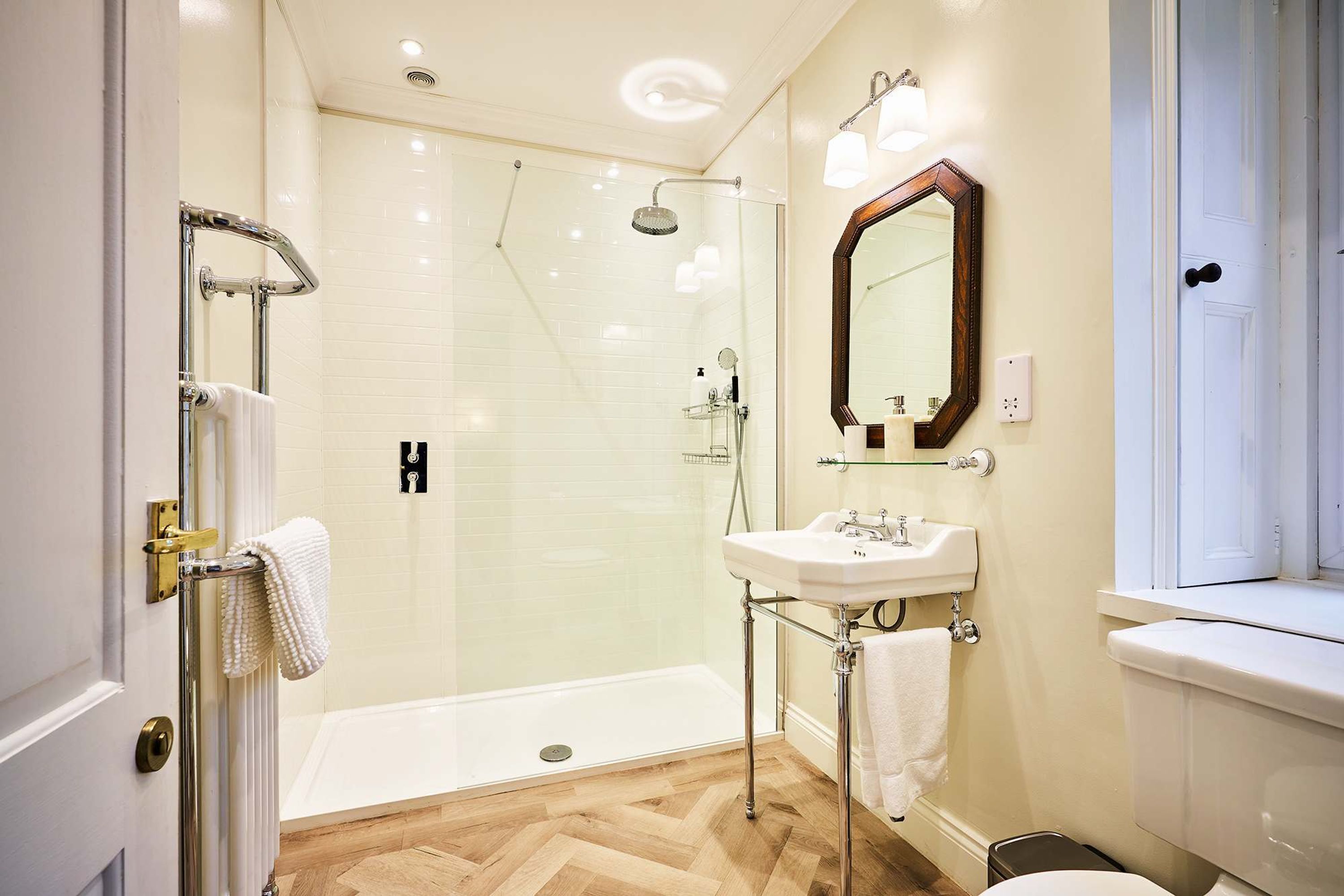 A modern bathroom with a glass shower enclosure, a white sink, and a large mirror.