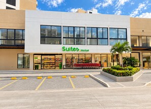 A Suites Market building with a modern facade, large windows, and a parking area in front. - Modern apartment for rent in Pozos Colorados, Santa Marta (Santa Marta)