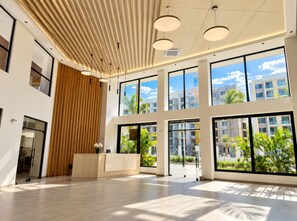 A spacious lobby with large windows, a wooden reception desk, and a high ceiling with modern lighting fixtures. - Modern apartment for rent in Pozos Colorados, Santa Marta (Santa Marta)