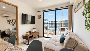 A modern living room with a sofa, a coffee table, a TV, and a balcony with a view of buildings. - Modern apartment for rent in Pozos Colorados, Santa Marta (Santa Marta)