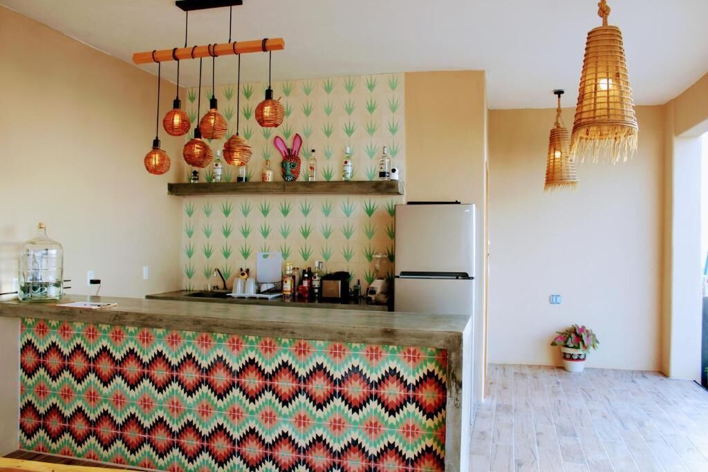 Eine Küche mit gemustertem Fliesenspiegel, hängenden Pendelleuchten und einem Kühlschrank.