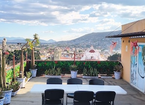 Ein Sitzbereich im Freien mit Blick auf Stadt und Berge.