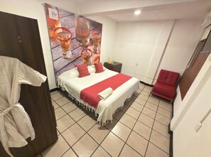 Ein Hotelzimmer mit einem Bett, einem roten Sessel, einem Nachttisch und einem Bild an der Wand.