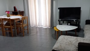 Ein Wohnzimmer mit Essbereich, einem Flachbildfernseher und einer Couch.
