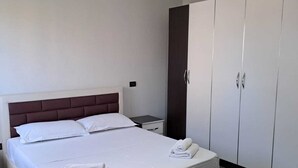 Ein modernes Hotelzimmer mit einem großen Bett, einem Nachttisch und einem Kleiderschrank.