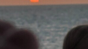 Un coucher de soleil sur l’océan, avec un premier plan flou.