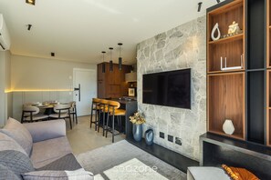 Uma sala de estar moderna com lareira de pedra, uma televisão de tela plana e uma área de refeições com banquetas.