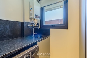 A compact kitchen with a built-in water heater, a window, and a dishwasher. - Sophisticated Apt Near Covered Street Dlh0403 (Gramado)