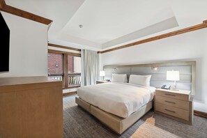A hotel room with a large bed, bedside tables, a desk, and a view of a brick building. - The Aspen Mountain Residences 40ABC - 3 Bedroom + Theatre Room Residence (Aspen)