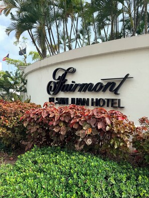 Schild des Fairmont San Juan Hotels mit einer üppigen, grünen Hecke im Vordergrund.