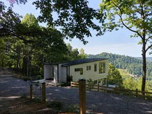 A modern two-story building with a gravel driveway and a wooden fence.