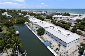 Una zona residencial costera con un puerto deportivo, edificios blancos y una vista despejada del océano.