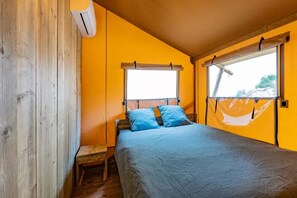 A bedroom with a bed, a window, and a wooden wall.