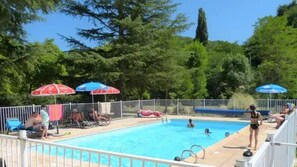 A swimming pool with a fenced area, lounge chairs, and umbrellas.