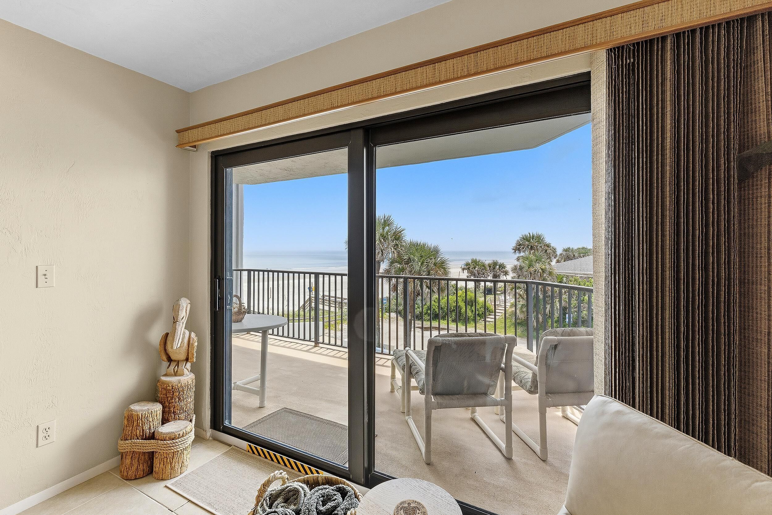 A balcony with a view of the ocean, a white sofa, and a statue.