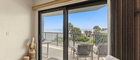 A balcony with a view of the ocean, a white sofa, and a statue.