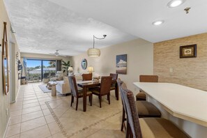 A spacious dining area with a high ceiling and a view of the outdoors. - Las Brisas 521 (New Smyrna Beach)