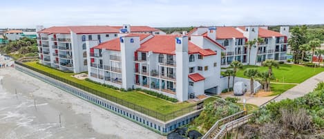 A beachfront hotel with multiple floors, red-tiled roofs, and balconies.