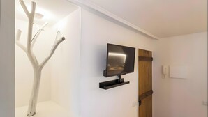Un interno moderno con una TV a schermo piatto montata a parete, una porta in legno e una parete bianca.
