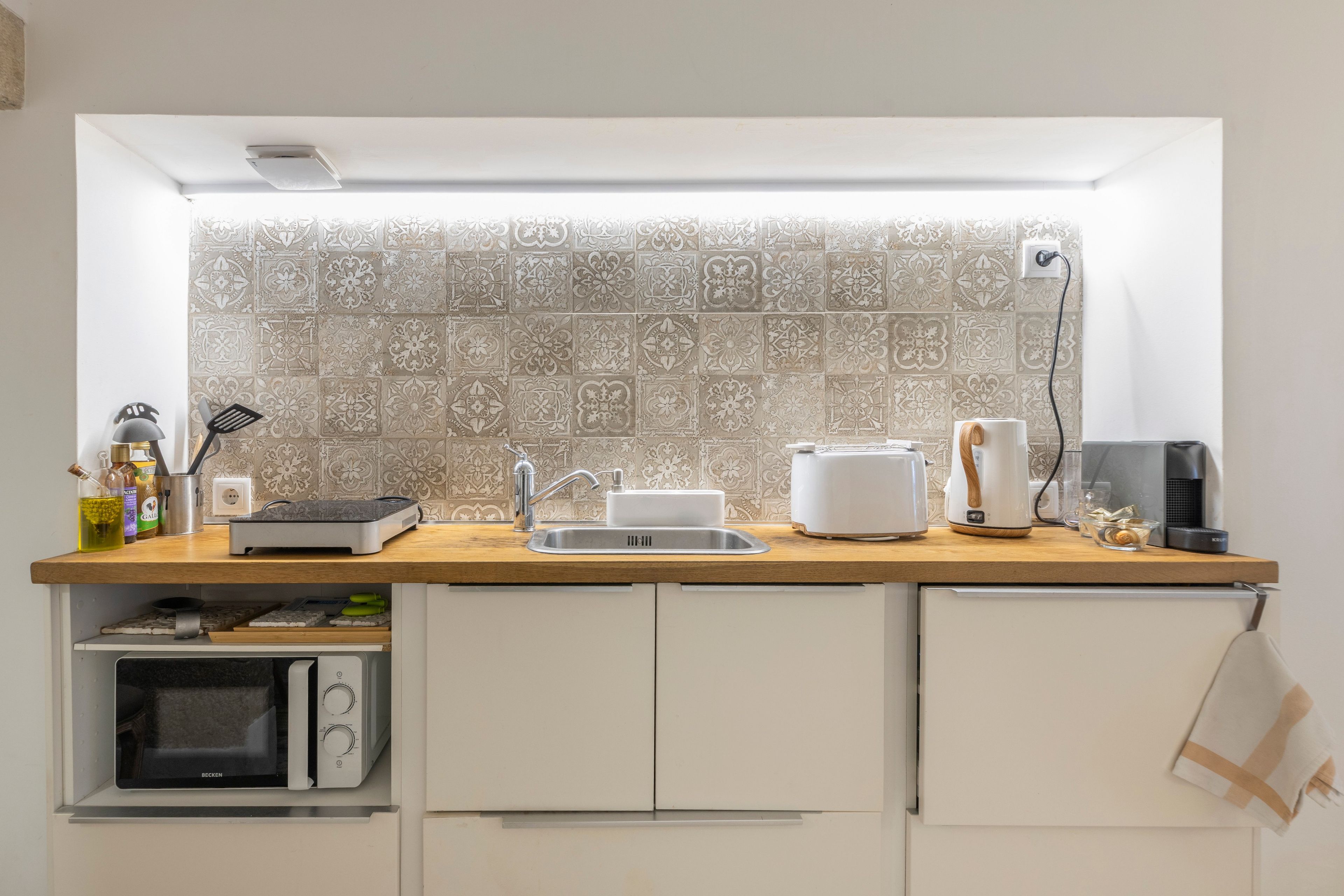 A compact kitchen with a built-in oven, a coffee maker, and a toaster on the counter.
