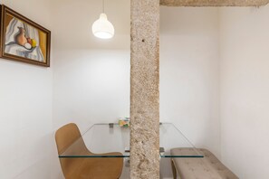 A modern room with a glass table, a brown chair, a hanging light fixture, and a framed artwork on the wall. - Apartment 'Sweet Rose Bairro Alto' with Balcony and Wi-Fi (Lisbon)