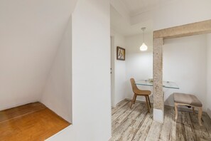 Et værelse med trægulv, et glasbord, en træstol, en polstret bænk og en hængende lampe.