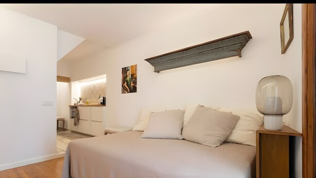 Una camera da letto con un letto, un comodino, una lampada e una mensola a parete.