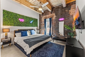 A modern bedroom with a bed, a green wall, a ceiling fan, and a TV. - 2BR Modern Retreat Escape | Downtown Memphis | Walking Distances | Arcade & Gym (Memphis)