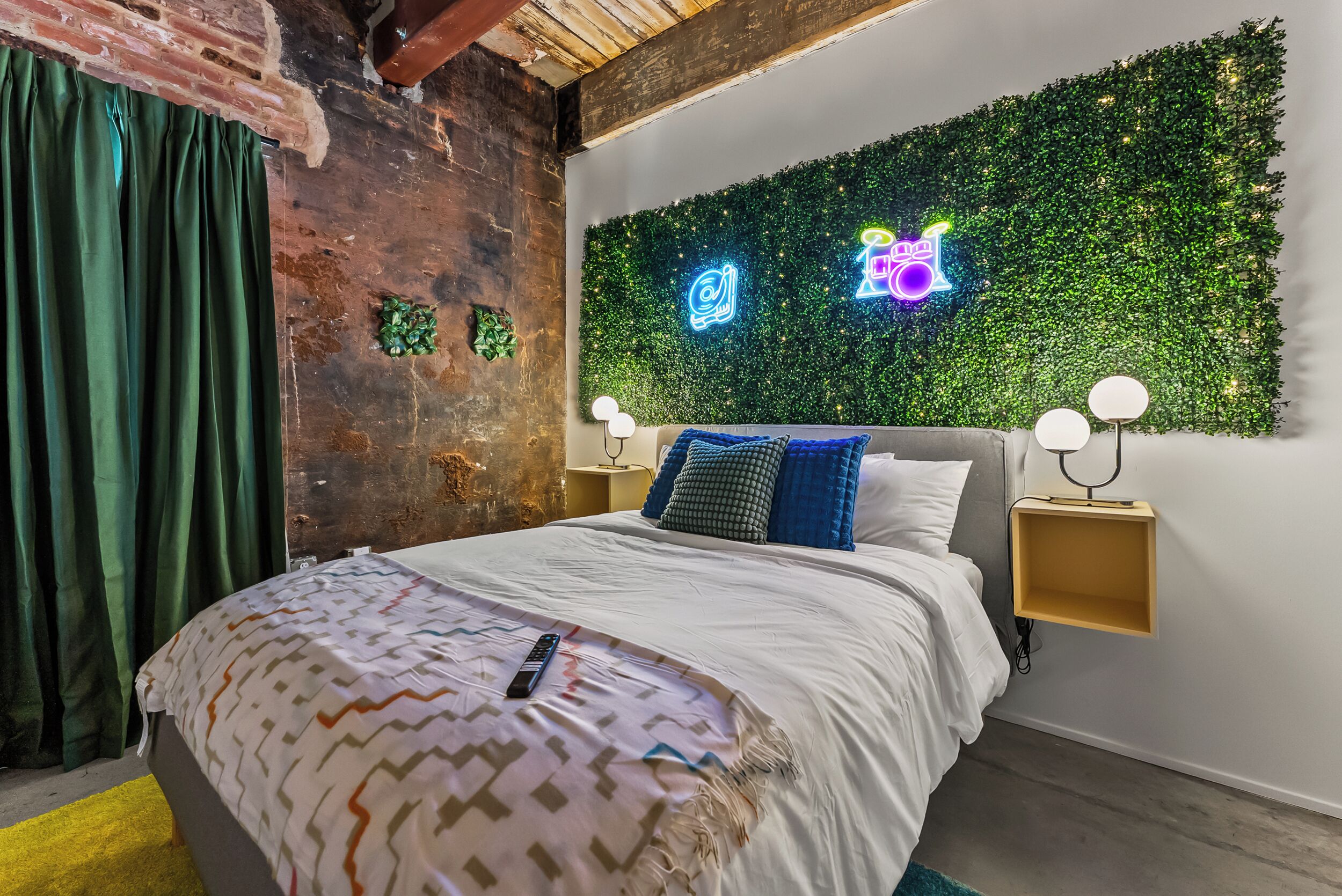 A bedroom with a bed, a neon sign, and a green wall.