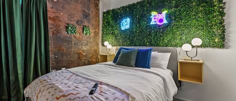 A bedroom with a bed, a neon sign, and a green wall.