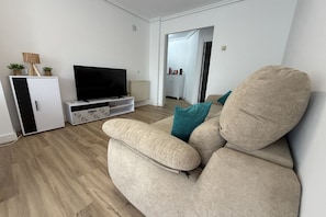 A living room with a beige sofa, a flat-screen TV, and a white cabinet.